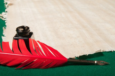 Red quill pen and black inkwell on a papyrus sheetの写真素材