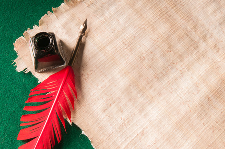 Red quill pen and black inkwell on a papyrus sheetの写真素材