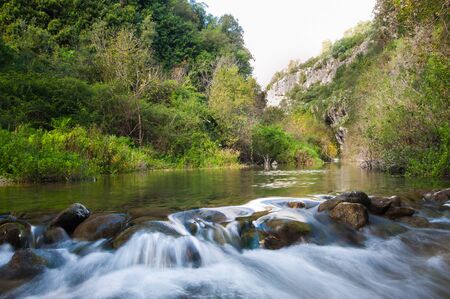 Anapo river flowing in the Pantalica valley, Sicily, and the walls of the canyon in the backgroundの写真素材