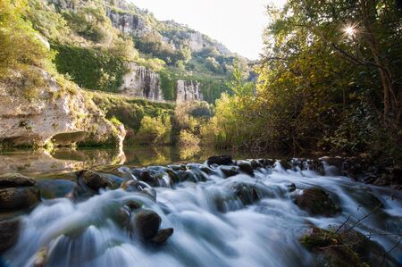 Anapo river flowing in the Pantalica valley, Sicily, and the walls of the canyon in the backgroundの写真素材