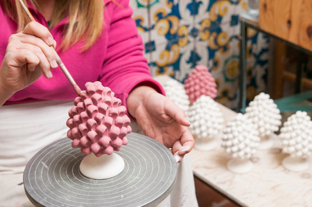 A pottery decorator painting a typical ceramic pine cone in his work table in Caltagirone, Sicilyの写真素材