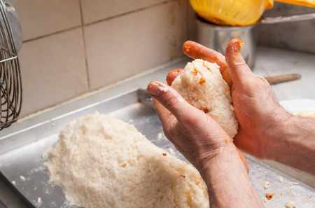 Hands of cook modelling a typical sicilian rice arancino in a cone shapeの写真素材