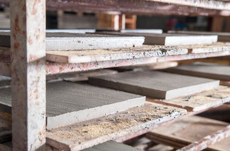 Just squared tiles made of clay and lavic sand set into a shelf before being firedの写真素材
