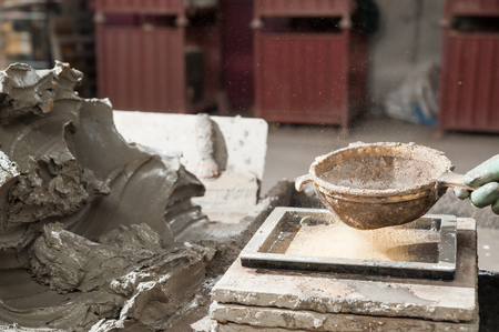 Red brick artisan strewing sawdust at the base of a mould before putting the clay to modelの写真素材