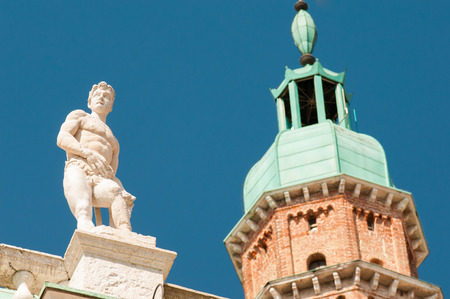Statues on the top of the Basilica palladiana, the main monument of the town Vicenza and the clock tower as a backgroundの写真素材