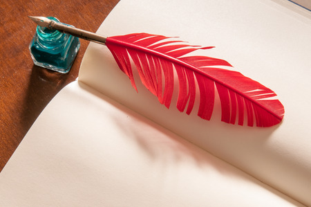 Red quill pen and green inkwell on an open sketchbookの写真素材