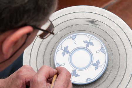 Ceramic artist in Caltagirone, Sicily, decorating some coffee saucers in his workshopの写真素材