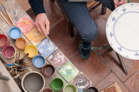 Ceramic artist in Caltagirone, Sicily, decorating a ceramic dish in his workshopの写真素材