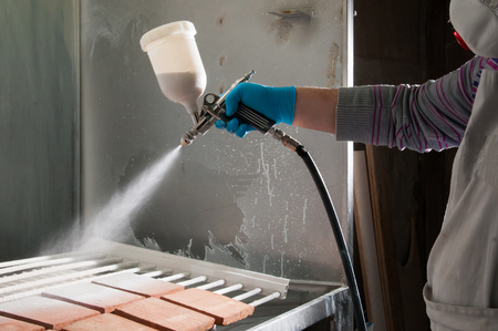 Pottery artisan in Caltagirone, Sicily, using an airbrush to enamel some square tilesの写真素材
