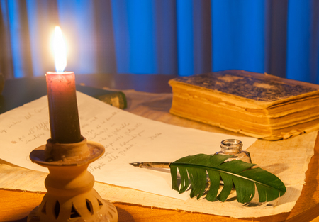 Closeup view of a candle with a quill and a letter in the backgroundの写真素材