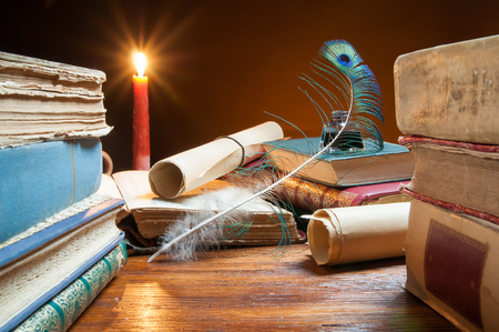 Quill pen, old papers and books by candle lightの写真素材