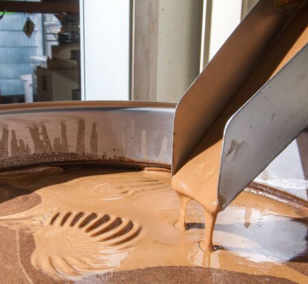 Hazelnut cream coming out from a industrial machine into a steel basinの写真素材
