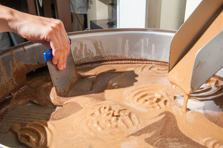Hazelnut cream coming out from a industrial machine into a steel basinの写真素材