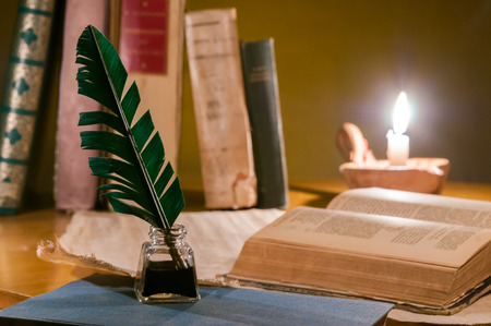 Quill pen, old papers and books by candle lightの写真素材
