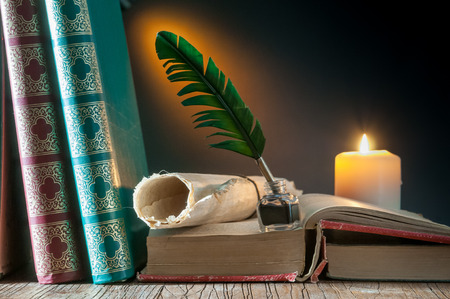 Green quil pen and black inkwell with old papers and booksの写真素材