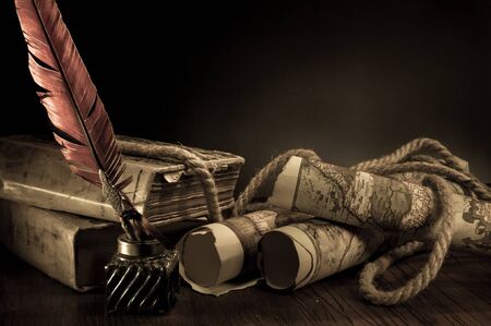Quill pen, inkwell and old rolled up maps and papers, vintage effect