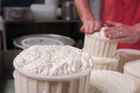 Farmer putting hot tuma cheese into plastic containers for sale