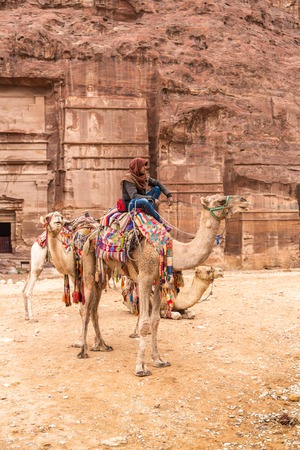 Petra, Jordan - October 26, 2015: Bedouin on a camel. Tour guide.  A walk on a camel. The service for tourists. The rainy season in Jordan. Petra is one the New Seven Wonders of the World.のeditorial素材