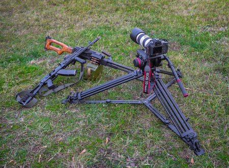 Odessa, Ukraine - December 02, 2015: The camera Canon and two machine guns lying on the grass. War...