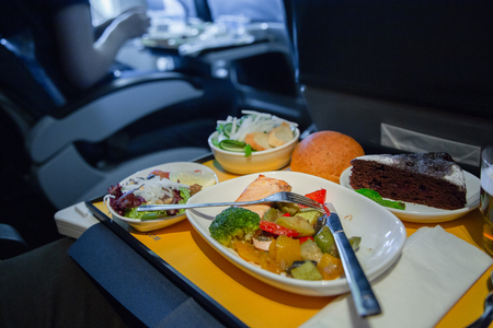 Passenger eats food on Board the plane. Food served on board of business class airplane on the table. Tray of food in the airplane. Tray of food on the plane, business class travel.の写真素材