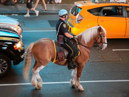 New York, United States - jun 21, 2016: Police officers ride their horses downtown in New York on on Times Square. New York Horse Police patrol the streets in busy traffic.のeditorial素材