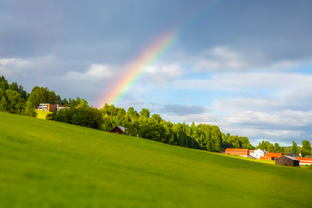 Rainbow near the house. Traditional colored wooden house in Norway at summer day. Country houses in village in Norway.の写真素材