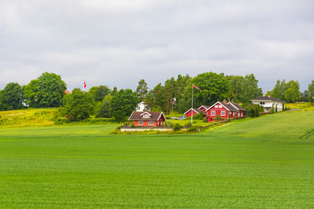 Traditional colored wooden house in Norway at summer day. Country houses in village in Norway. Traditional norwegian wooden house. Typical countryside Norwegian landscape with red painted wall house.の写真素材