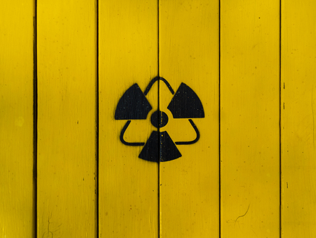 Sign of radiation on a yellow wooden board. Radioactive sign - symbol of radiation. Yellow and black radioactive hazard (ionizing radiation) nuclear danger warning symbol.の写真素材