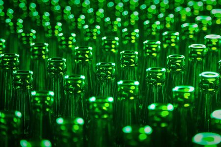 Glass bottle texture pattern. Glass bottle at factory for production of glass containers. Green Beer Bottle Neck. Many of transparent green glass bottle into row, close up.の写真素材