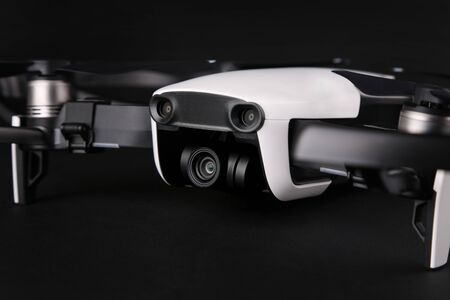 Drone isolated on black background,close up. New black white drone quadcopter with digital camera and sensors flying isolated on dark background, close up. Camera and sensors on a small drone.の写真素材