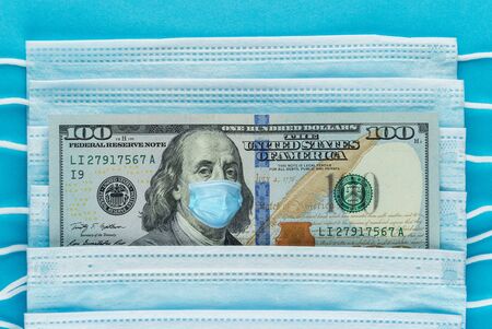 Medical mask on a banknote of 100 dollars, concept of the global financial crisis. Medical mask or...