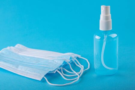 Coronavirus protective equipment - medical protective mask and antiseptic sanitizer spray. Medical mask and sanitizer on blue background. Coronavirus prevention medical masks and hand sanitizer spray.の写真素材