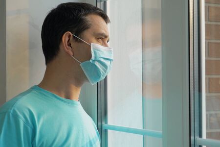 Home quarantine, self-isolation because of the Coronavirus disease, COVID-19. Man in a medical mask...