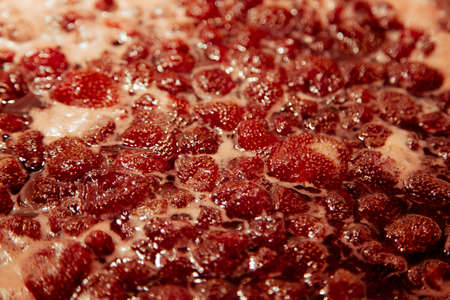 Strawberry jam simmering slightly, detailed close-up, top view. Beautiful strawberry jam in cooking...