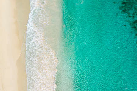 Aerial Top view of sand beach and blue sea. Aerial shot of golden beach meeting deep blue ocean water and foamy waves. Aerial beach top view overhead seaside. Ocean Beach, travel and vacation.の写真素材