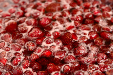 Strawberry jam simmering slightly, detailed close-up, top view. Beautiful strawberry jam in cooking process. Boiling homemade strawberry jam. Making a homemade Strawberry Jam. Boiling fruit into a panの写真素材