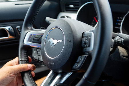 Los Angeles, CA, USA - April, 2017: Steering wheel of an American Ford Mustang muscle car with the driver's hands. Interior of modern model of Ford Mustang. Ford Mustang car steering wheel.のeditorial素材