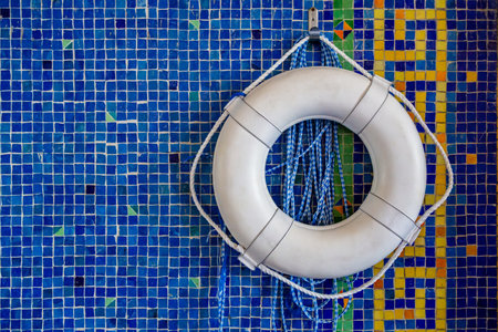 Vintage white life buoy hangs from an antique blue and gold colored mosaic tile. Lifebuoy close up on a vintage blue background. White lifebuoy on a blue tile wall. Background, copyspaceの写真素材
