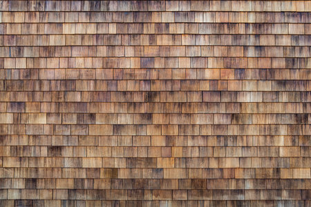 Wood Shake Wall. Building wall. Wood shake. Grunge cedar tile panel on the exterior wall. Grunge cedar tile panel on the exterior wall. House wall covered with small wooden tiles as a backgroundの写真素材