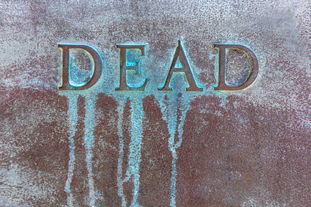 DEAD: Lettering DEAD on a bronze plate. Close-up of word DEAD on a bronze slab with oxidized green patina. Inscription DEAD on a bronze monument. Green patina streaksの写真素材