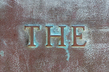 THE: Lettering THE on a bronze plate. Close-up of definite article THE on a bronze slab with oxidized green patina. Inscription on a bronze monumentの写真素材