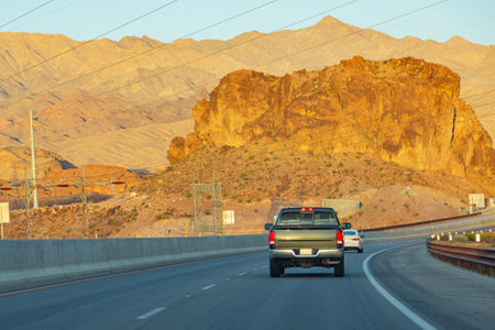 American highway with cars. Road stretches into distance against backdrop of mountains. Car drive far along the highway, rear viewの写真素材