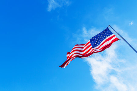American Flag blowing in the wind with a blue sky background. USA American Flag. Memorial Day, Independence Day - American conceptの写真素材
