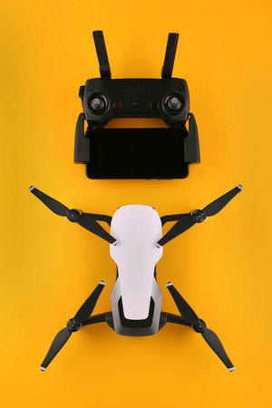 Drone quadcopter with a remote control and a smartphone is ready to fly. Remote control drone top view on isolated yellow background. Flat lay drone on a yellow background. Modern drone top view.の写真素材