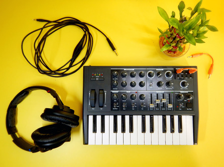 Synthesizer on yellow background with orange patch cables and headphonesの写真素材