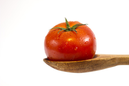 Tomato in a wooden spoon with white backgroundの写真素材