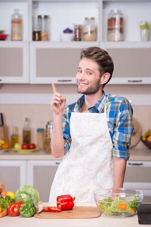Portrait of a smiling young man trying to cook dinner in kitchenの写真素材
