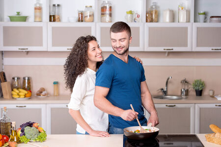 Portrait of a beautiful couple preparing supper and looking at each otherの写真素材