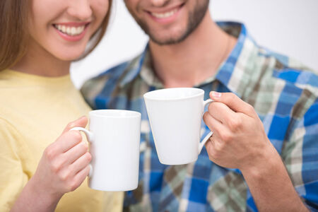 Close up of  smiling couple holding two cups of coffeeの写真素材