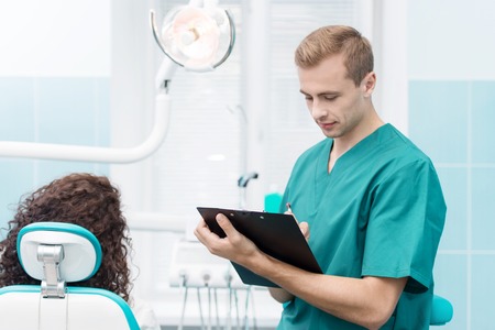 Portrait of a young dentist at his dental office with patientの写真素材